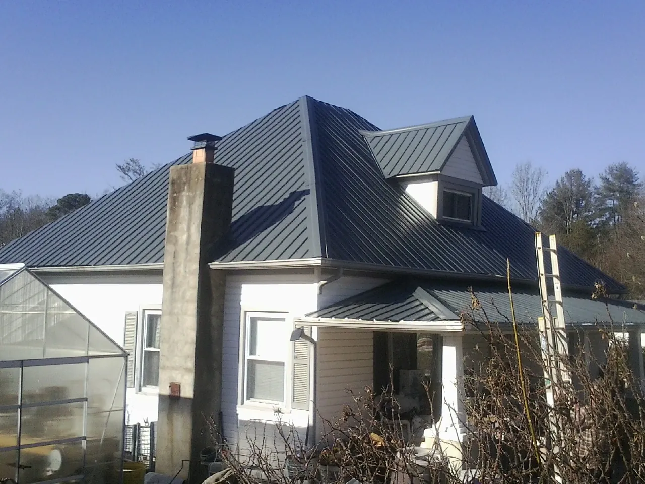 Dark blue standing seam metal roof on a white farmhouse with dormer — Slate & Tile Roof Repair by Roofing Brothers in Exton