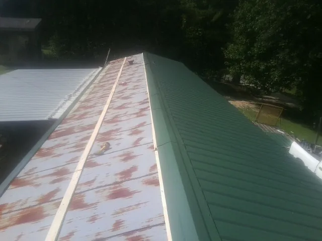 Old rusted panels beside newly installed green metal roofing — Wind Damage Roof Repair by Roofing Brothers in Exton
