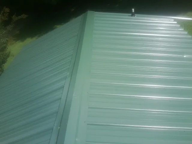 New green metal panels meeting at the ridge of a roof — Flat Roof Repair work by our crew in Exton