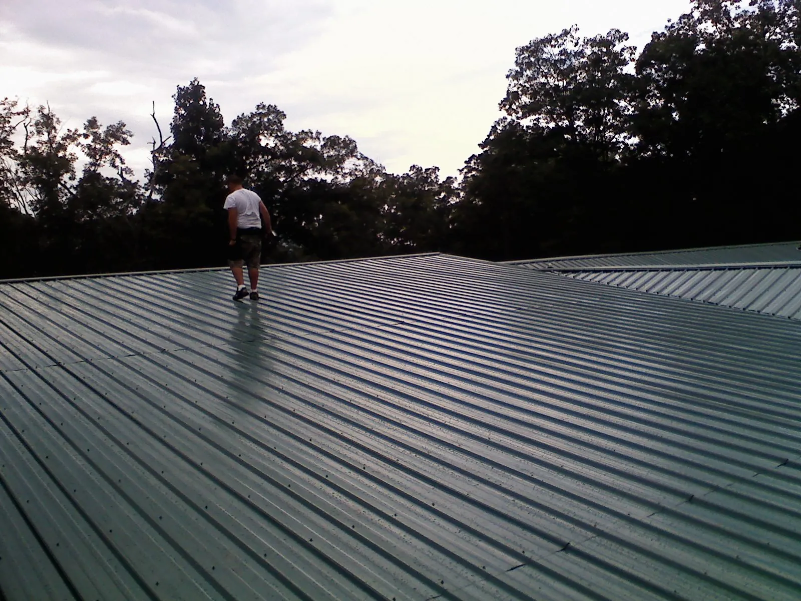 Roofer walking a wide expanse of new green metal roofing in Exton