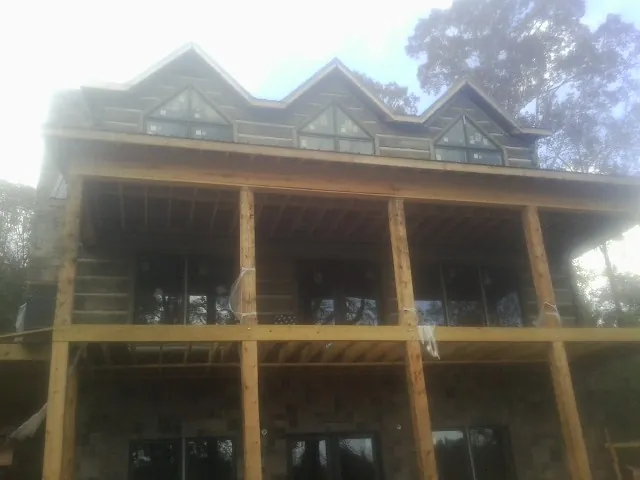 Dormers and porch framing on a large log home under construction — Roof Coating work by our crew in Exton