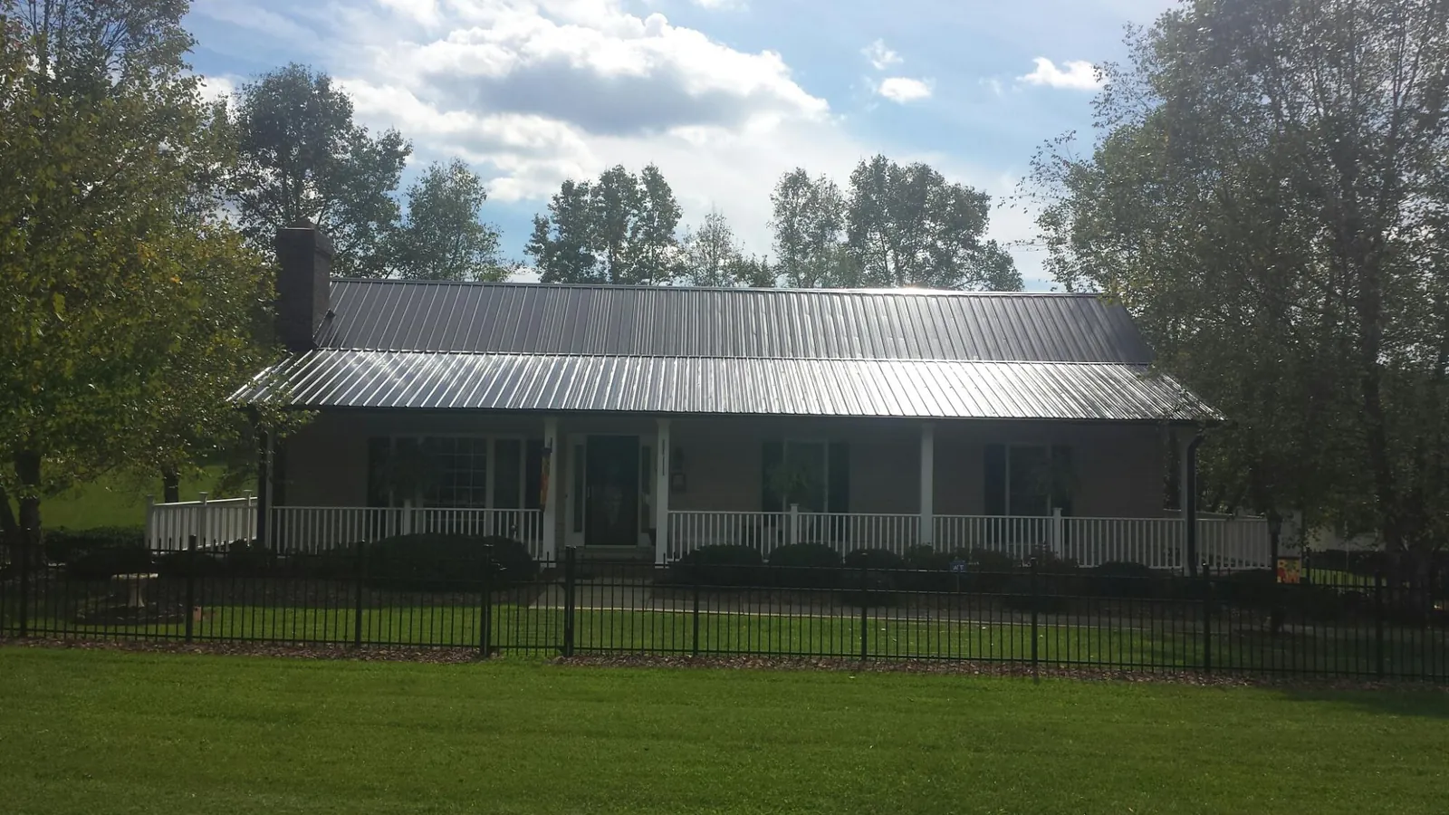Gray metal roof on a brick ranch with a full width front porch — Gutter Guard Installation work by our crew in Exton