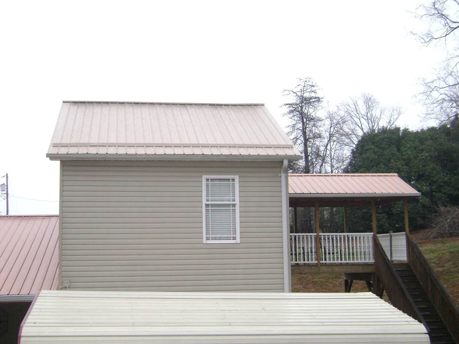Tan metal roofs on a two story addition and attached porch, from a Roof Replacement job in Exton